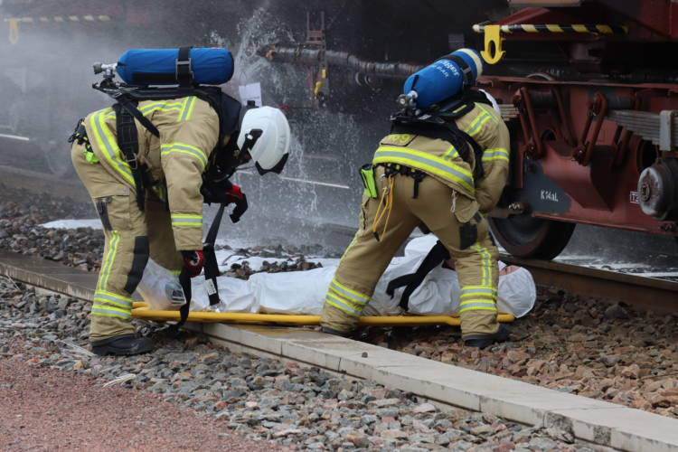 Pelastuslaitoksen työpari pelastaa ihmisen vuotavan junansäiliön vierestä.